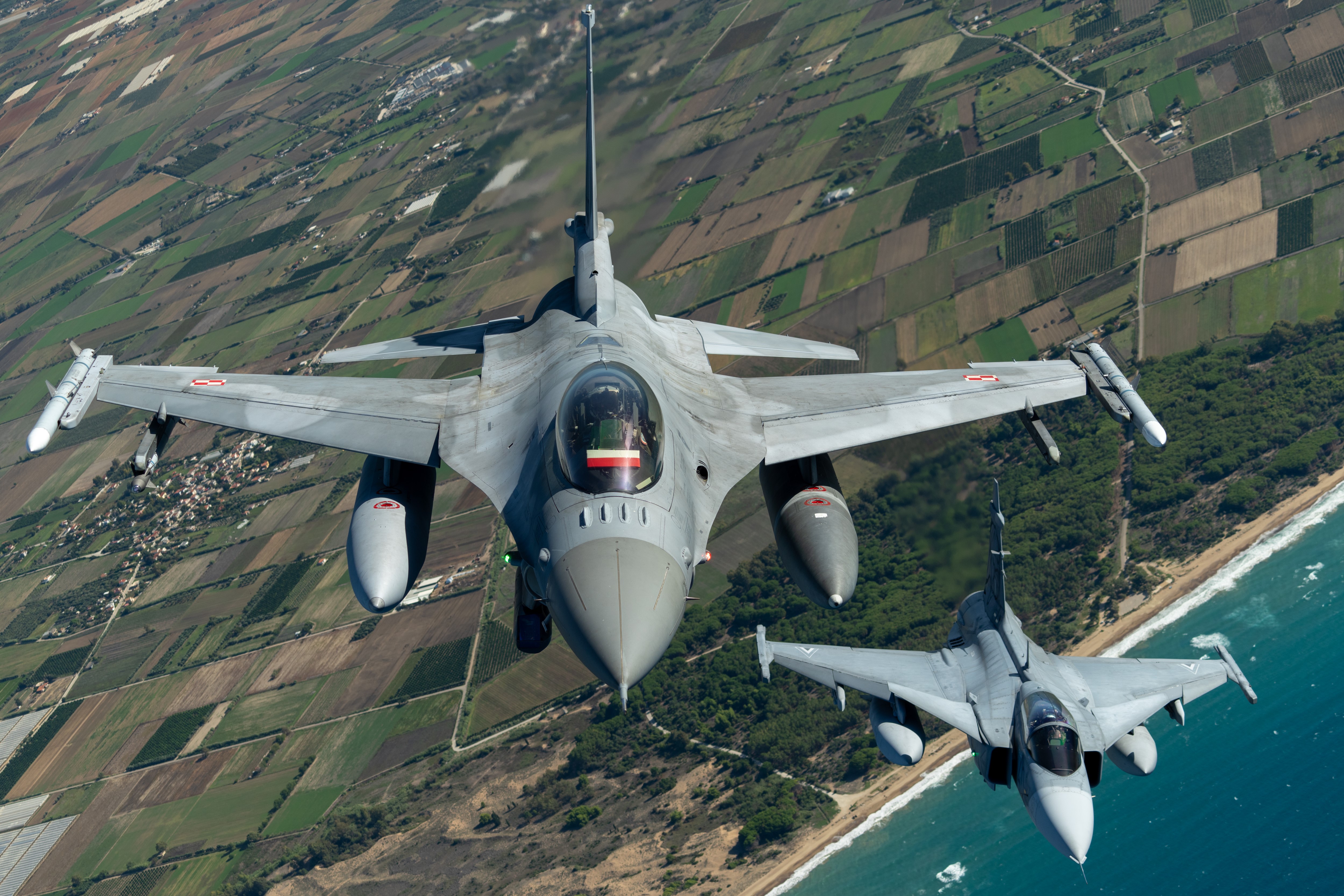 Polish Air Force F-16 and a Hungarian Air Force Gripen fly in formation during a training sortie over Greece